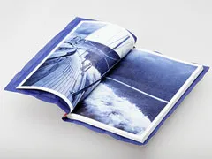 Aufgeschlagenes Buch mit blauer Fotografie eines Segelschiffs